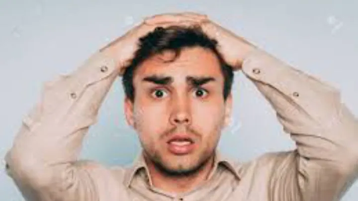 Young man holding his head looking confused and surprised while thinking.
