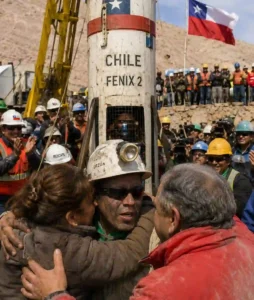 Chilean miner reunited with loved ones beside the Fénix 2 rescue capsule after the 2010 rescue of 33 miners trapped underground for 69 days.